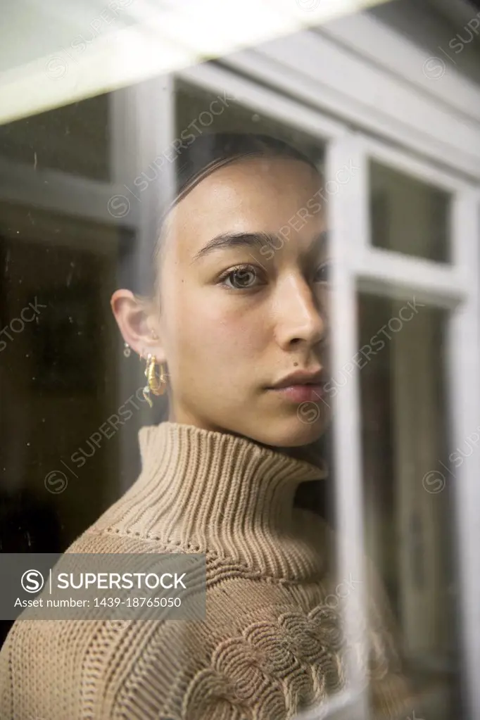 Portrait of young woman reflected in window