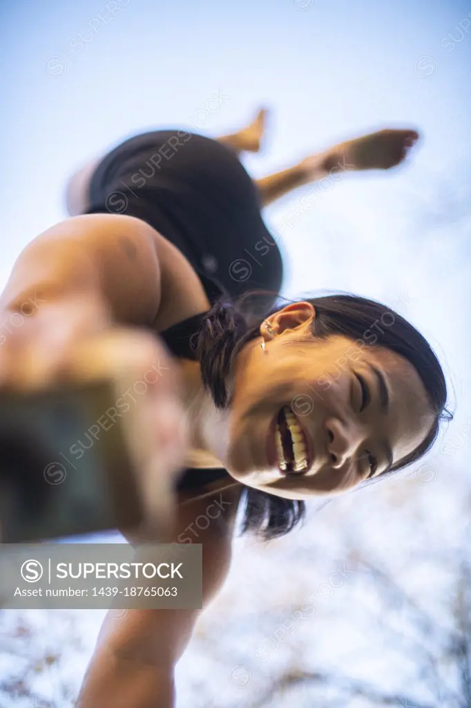 Female gymnast performing handstand outdoors seen from below