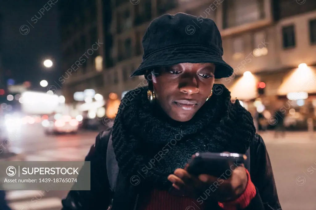 Italy, Woman looking at smart phone in city at night
