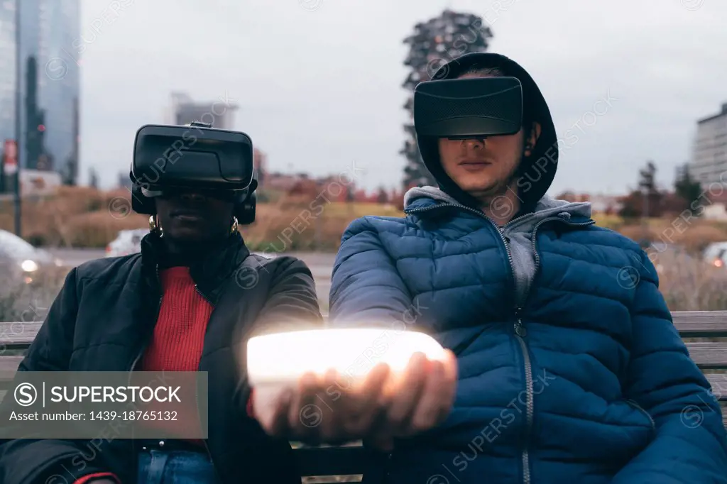 Italy, Couple with VR goggles holding glowing object in city