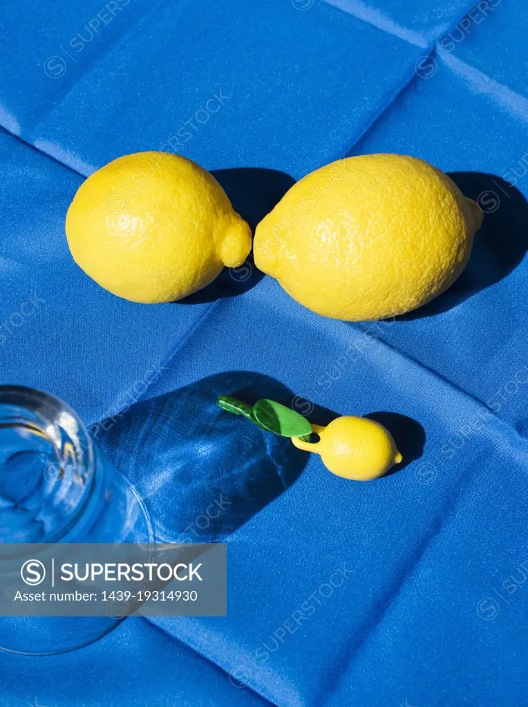 Still life with glass and lemons on blue tablecloth