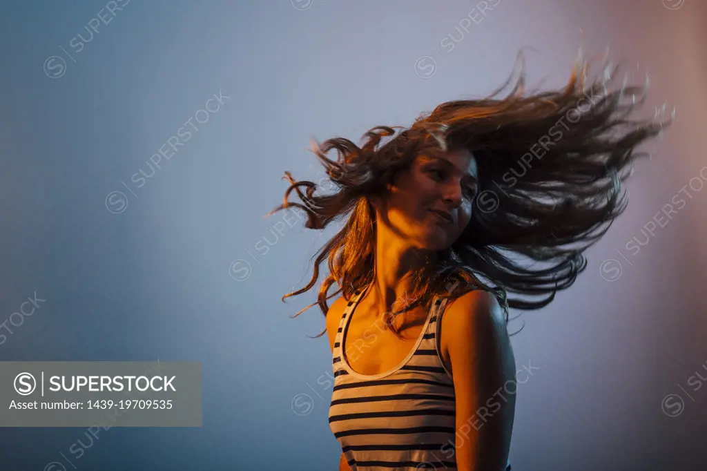 Studio shot of young woman throwing hair