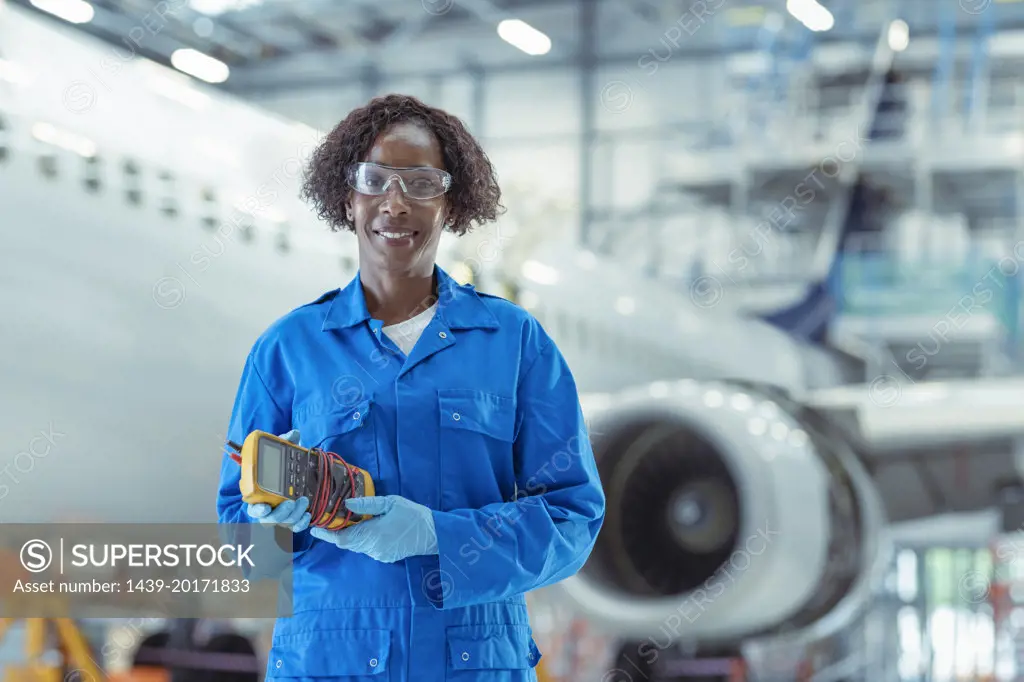 Portrait of female apprentice aircraft maintenance engineer in hangar