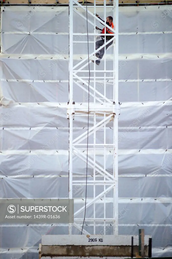 Construction worker climbing up a metal tower 