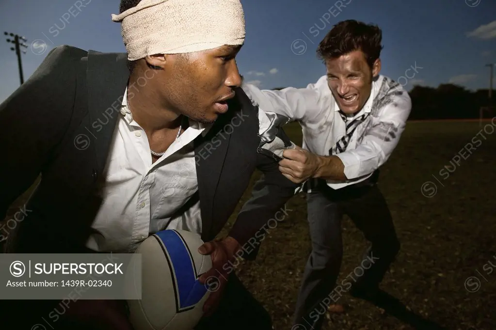 Businessmen playing rugby