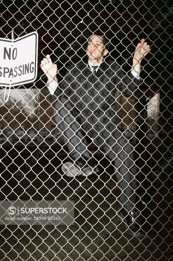 Businessman climbing a fence