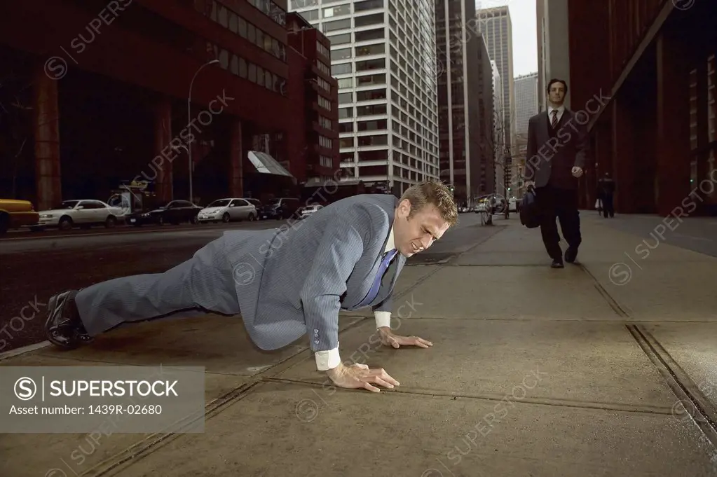 Businessman doing push ups in street