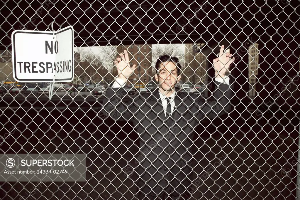 Businessman trapped behind fence