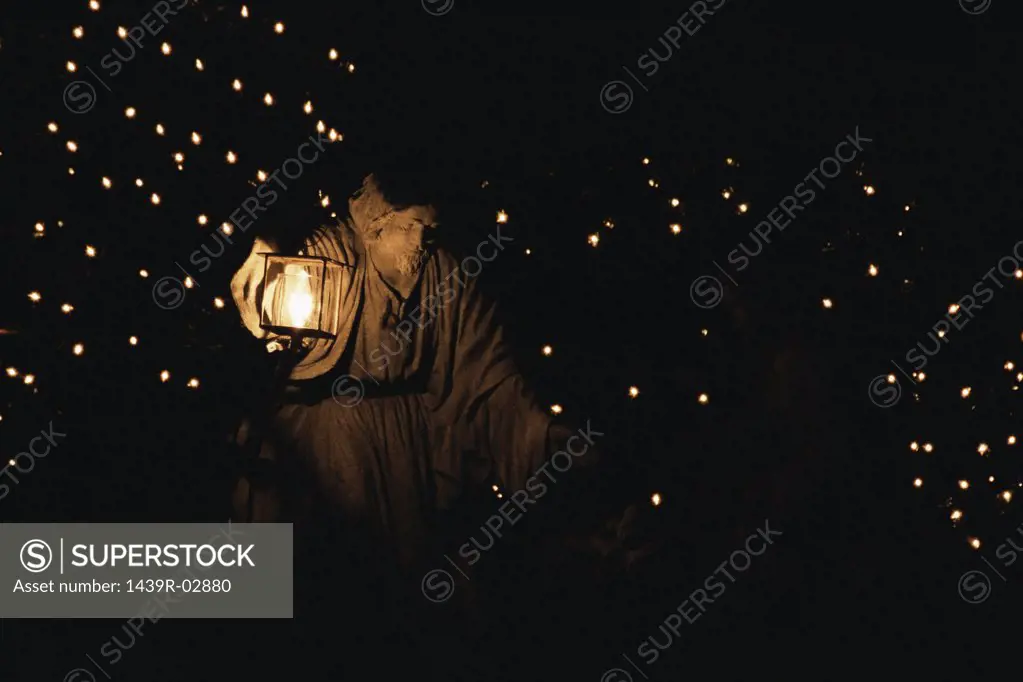 Statue of a man holding an illuminated lantern