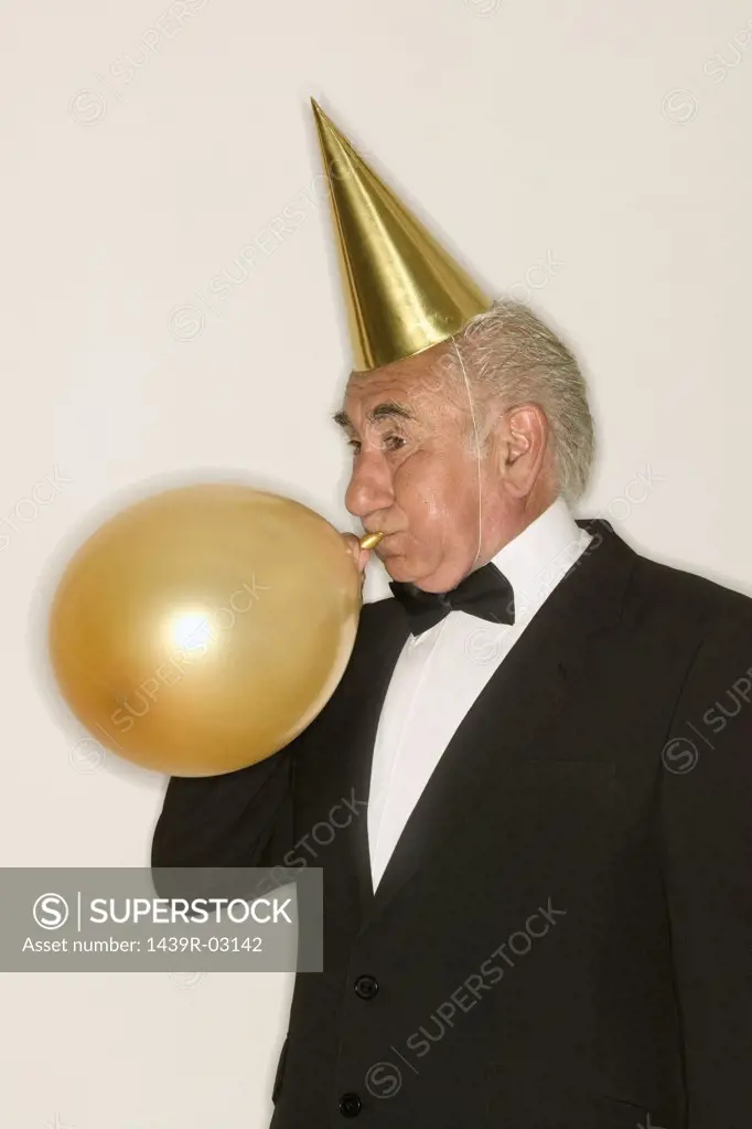 Senior man inflating a balloon