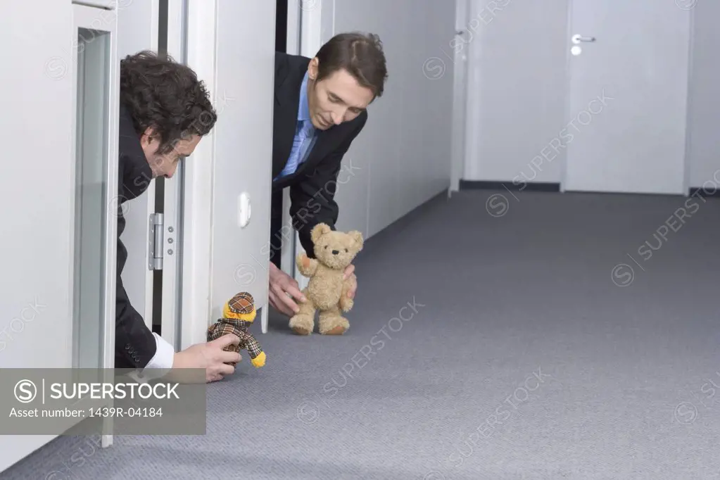 Businessmen playing with teddy bears