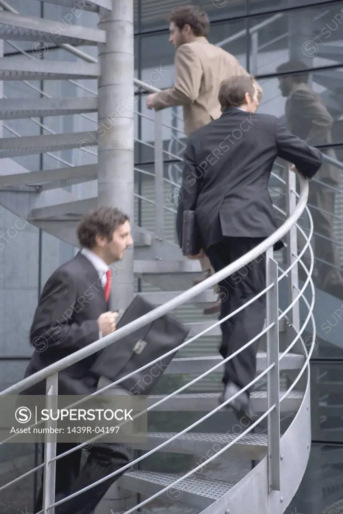 Businessmen running up spiral staircase