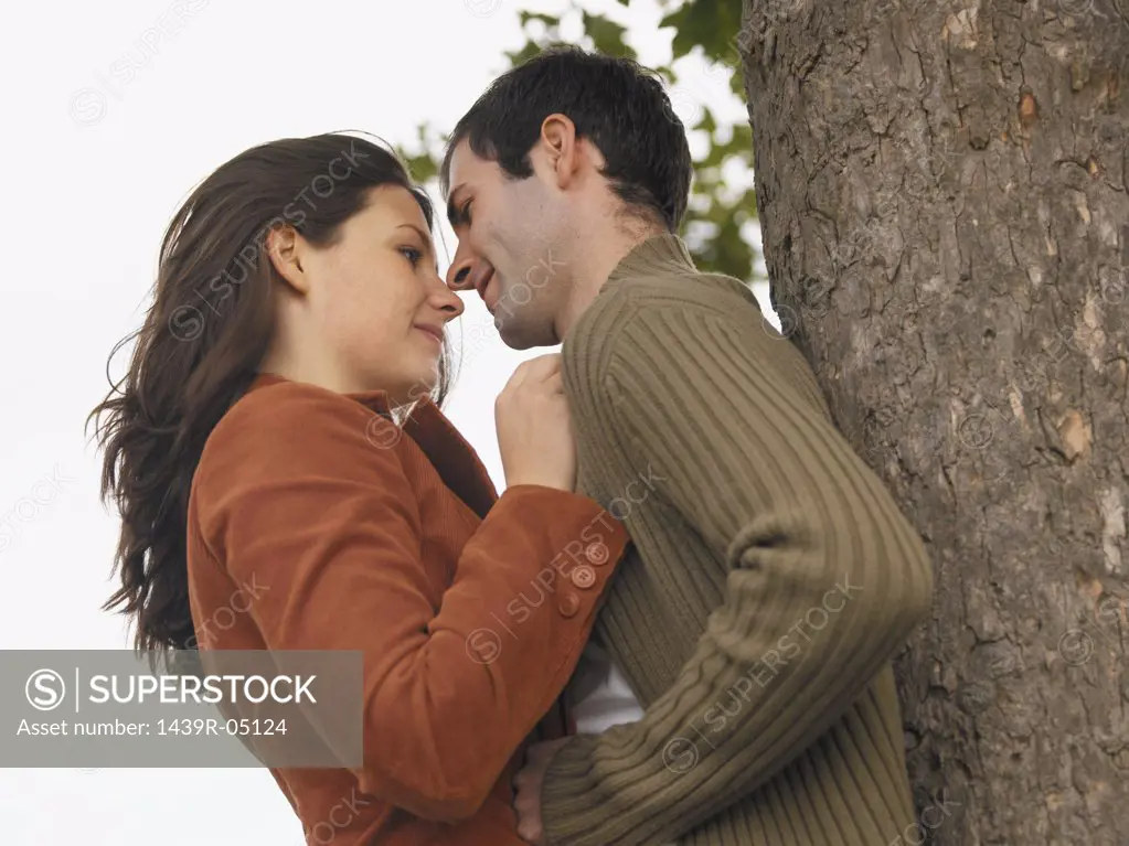 Couple hugging against tree