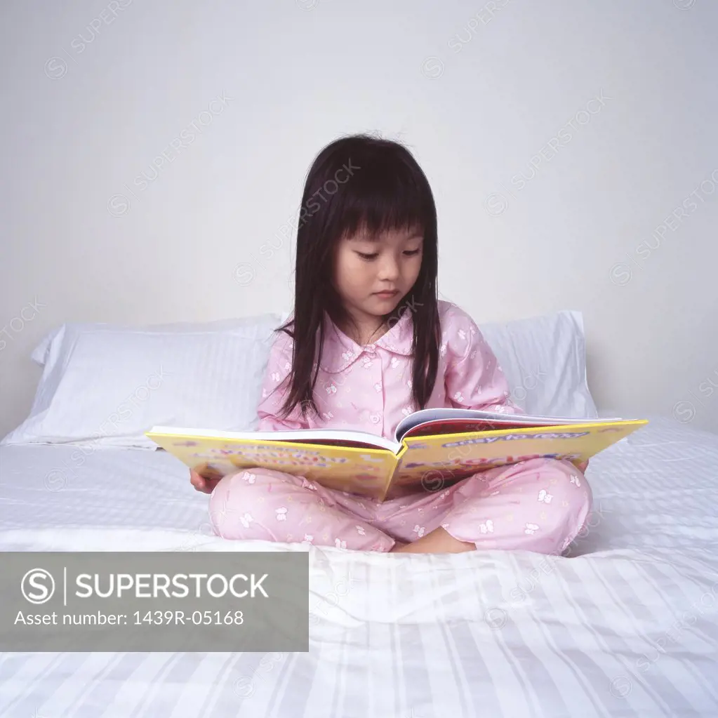 Young girl reading on bed