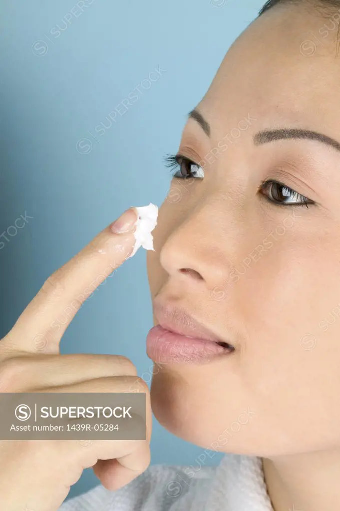 Woman applying moisturiser to cheek