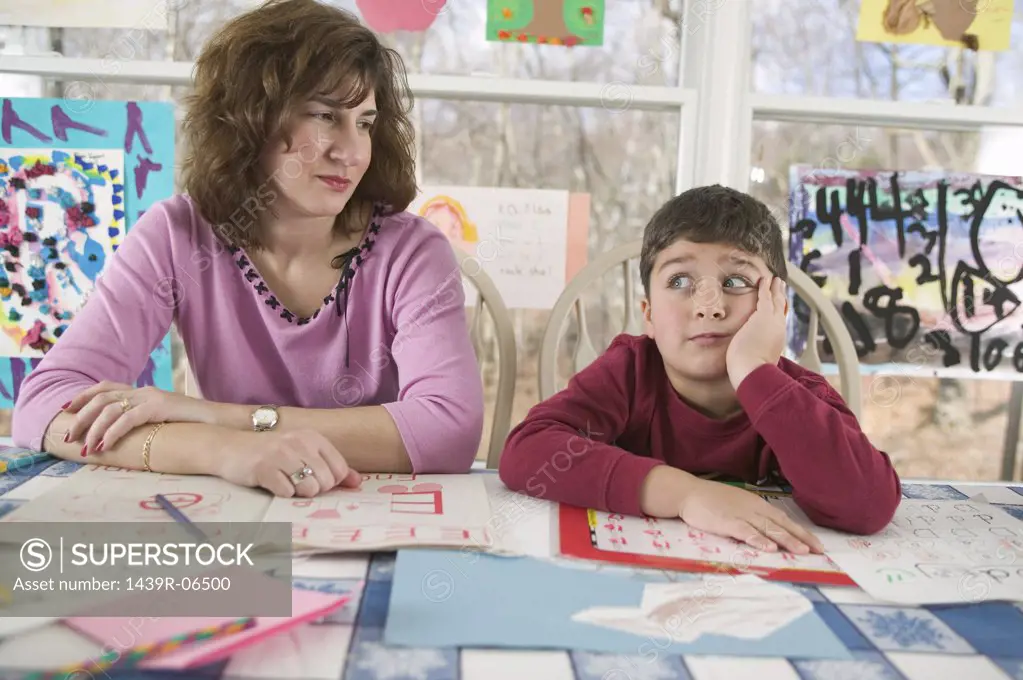 Mother helping bored son with homework