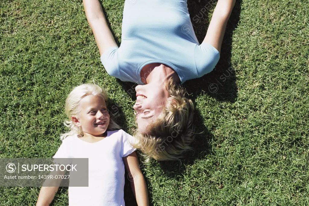 Mother and daughter lying on lawn