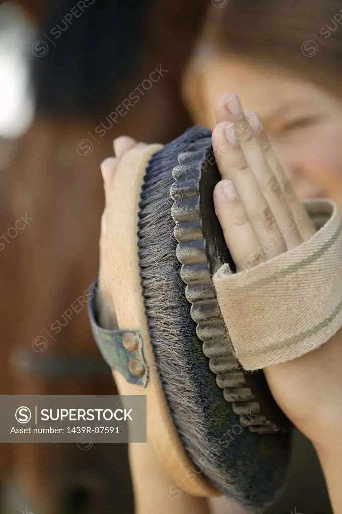 Young woman cleaning horse's brush