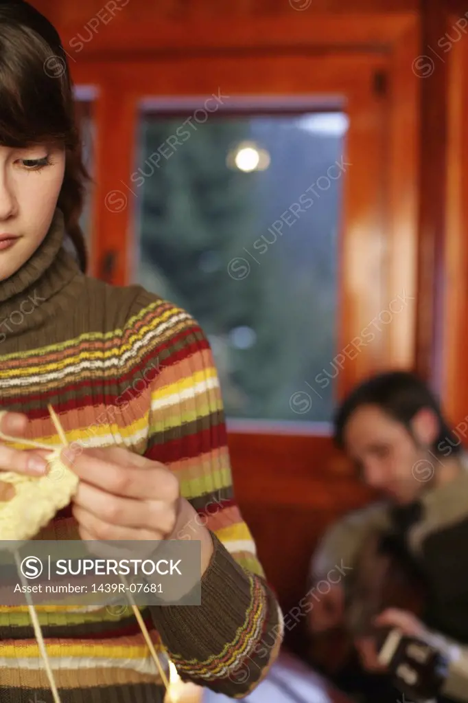 Woman knitting as man plays guitar