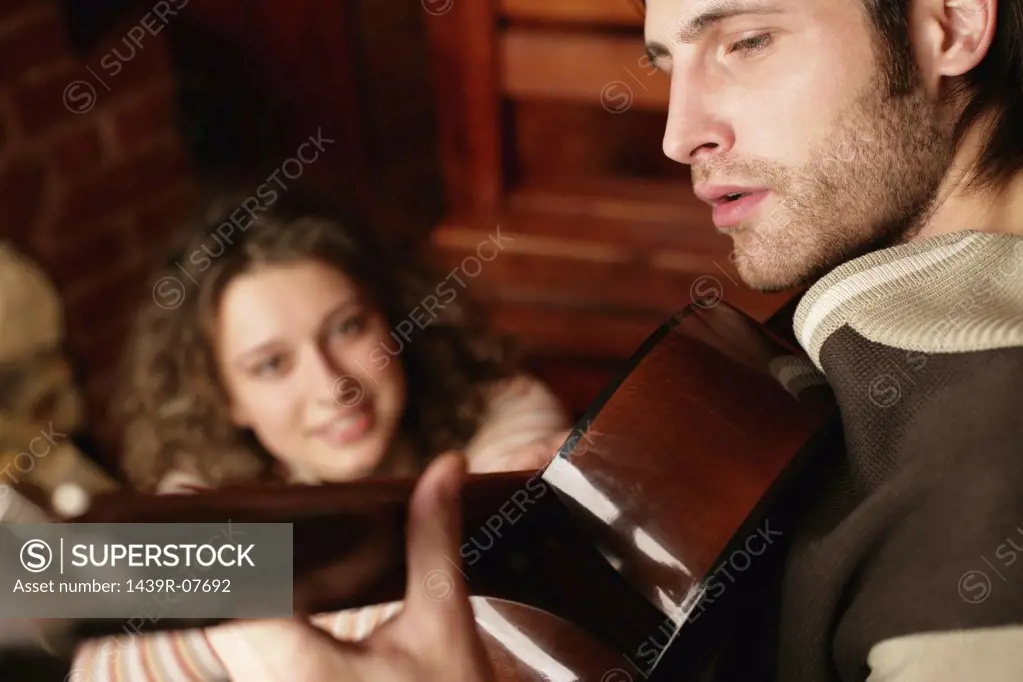 Woman listening to man play guitar