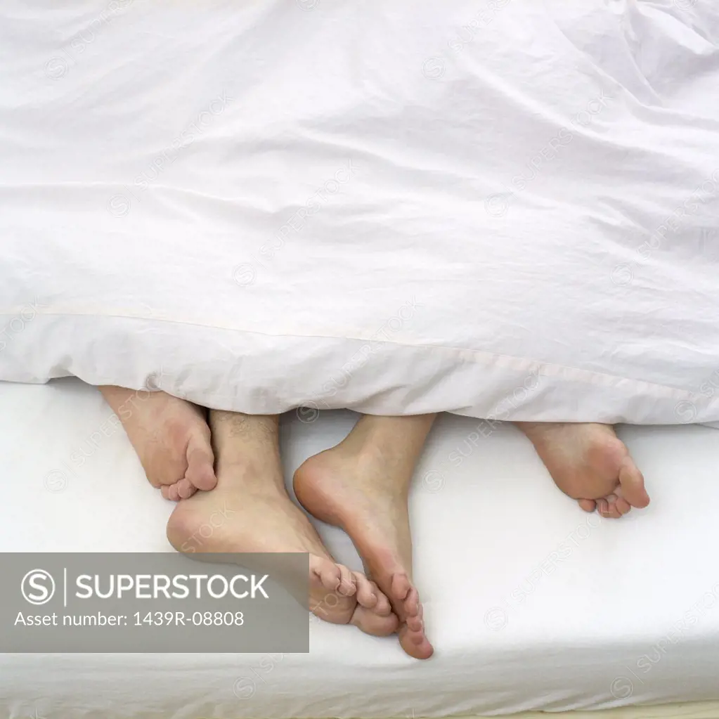 Bare feet of couple in bed