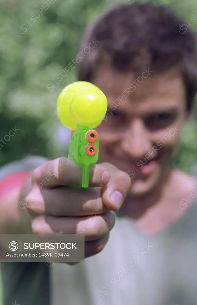 Young man aiming water pistol.