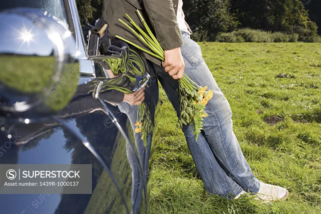 Man with flowers leaning on car