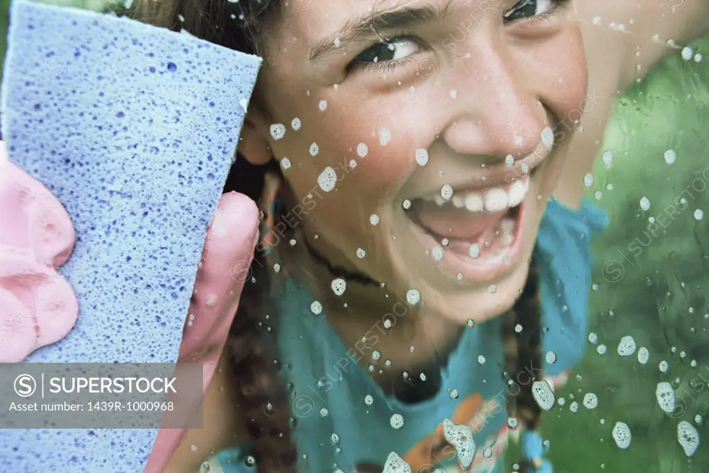 Girl cleaning glass with sponge