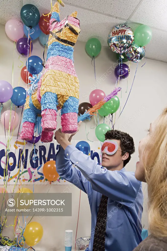 Office workers playing with a pinata