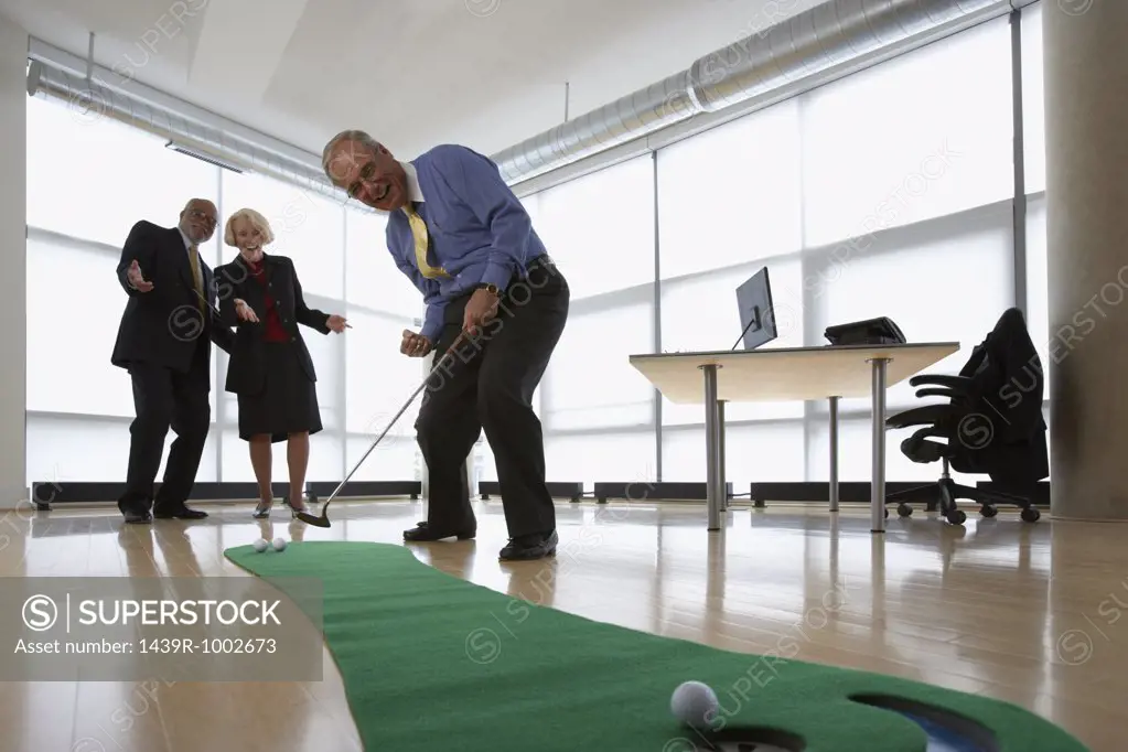 Three senior office workers practicing putting