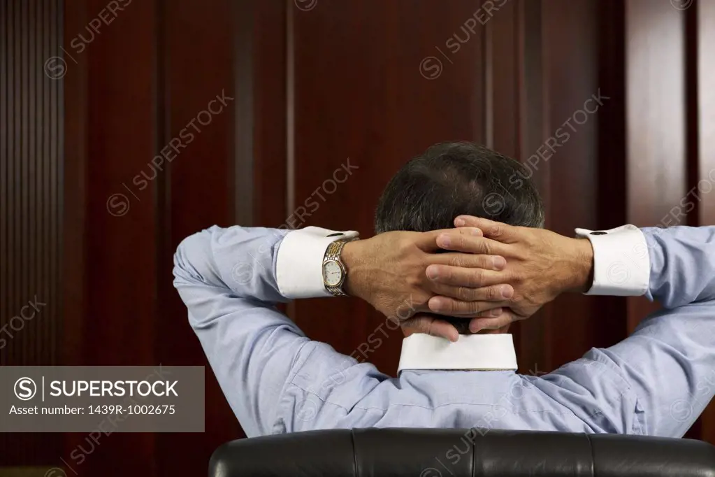 Businessman relaxing with hands behind head
