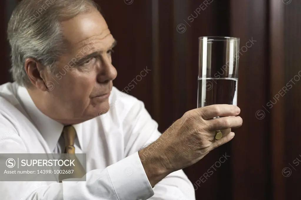 Businessman looking thoughtfully at glass of water