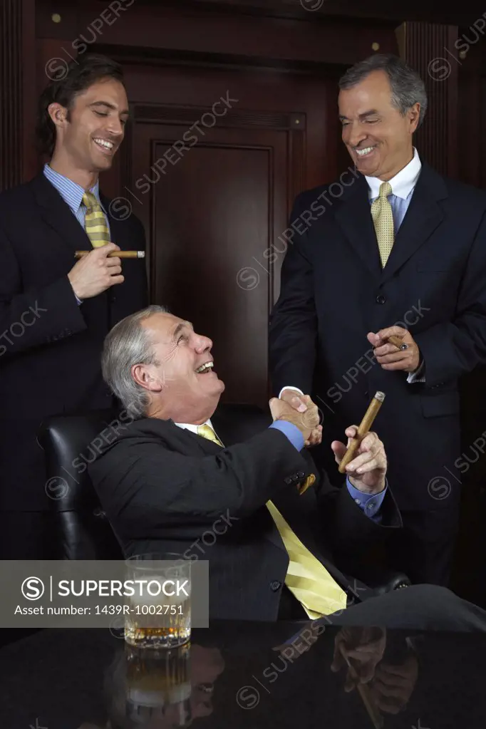Three businessmen celebrating with cigars
