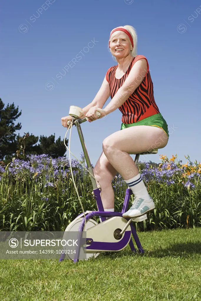 Senior adult woman riding an exercise bike