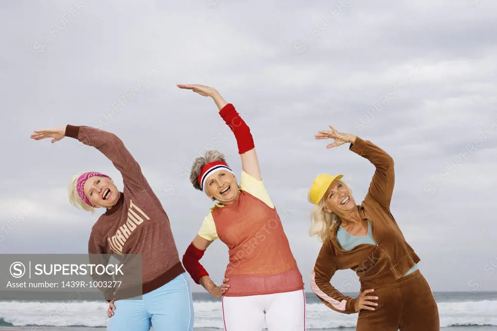 Three senior women stretching on beach