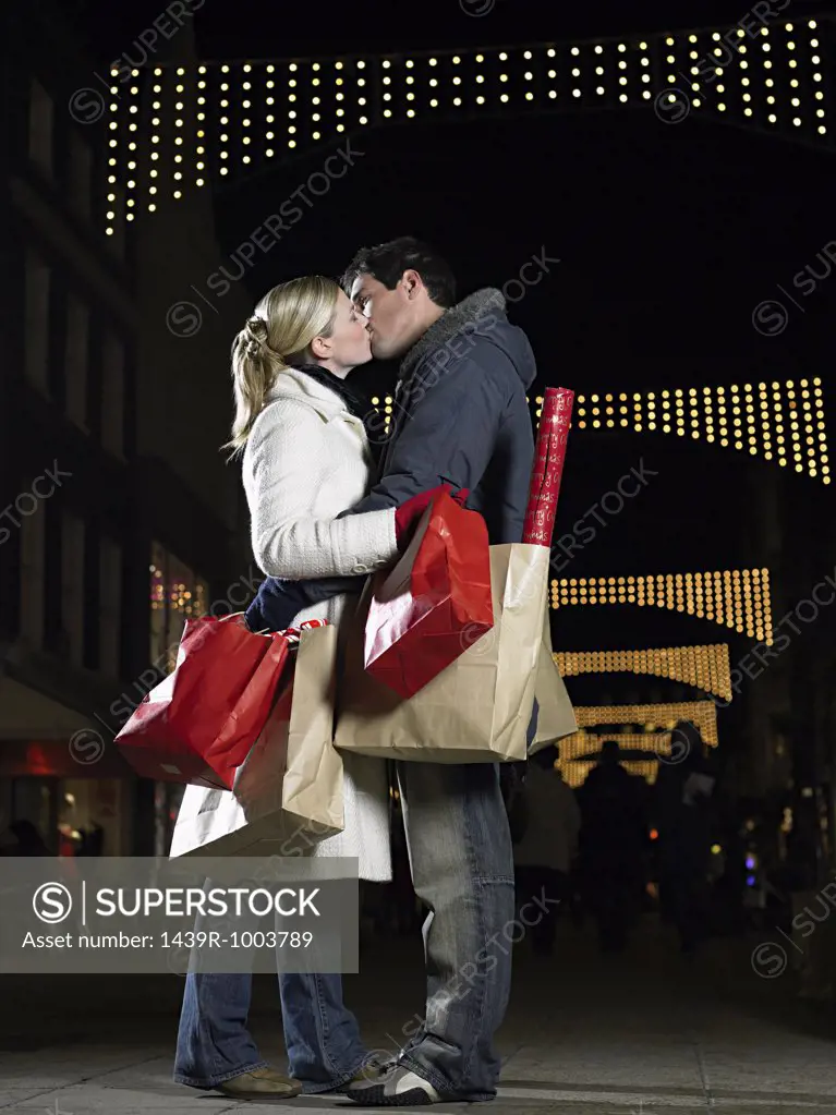 Couple kissing whilst christmas shopping