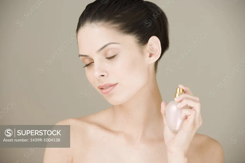 Young woman spraying perfume