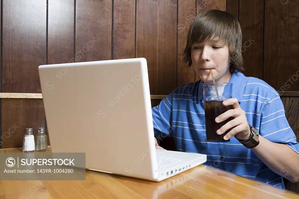 Teenage boy working on laptop in cafe