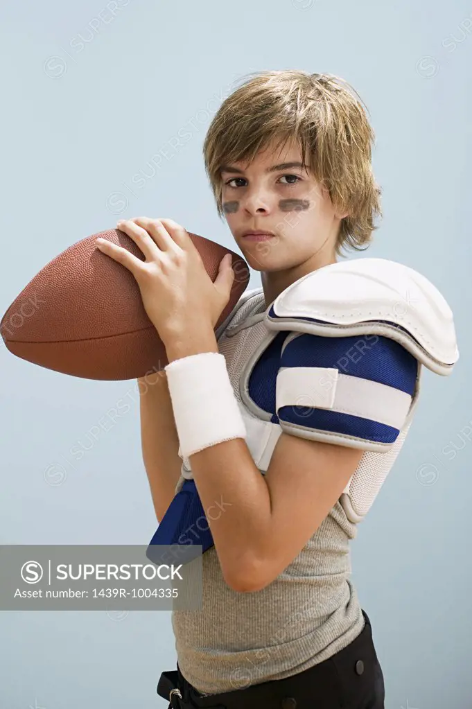 Boy in american football uniform holding ball