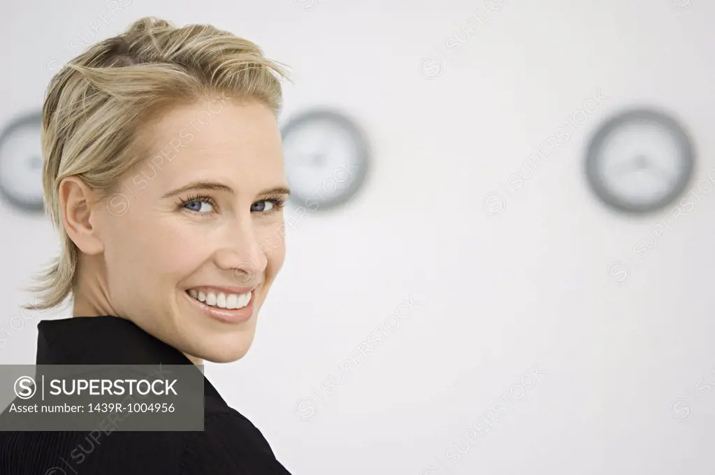 Businesswoman stood in front of three wall clocks