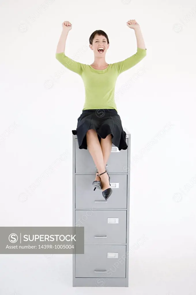Woman sat on top of a filing cabinet