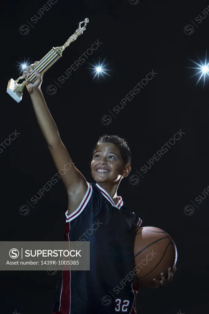Boy holding up a basketball trophy