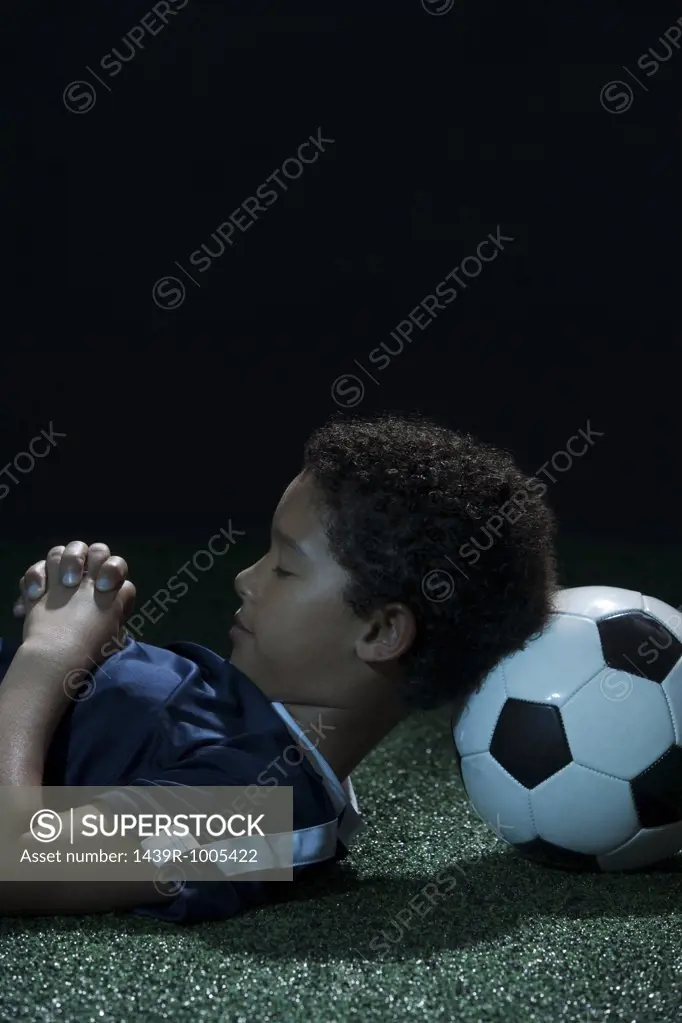 Boy sleeping with football as pillow