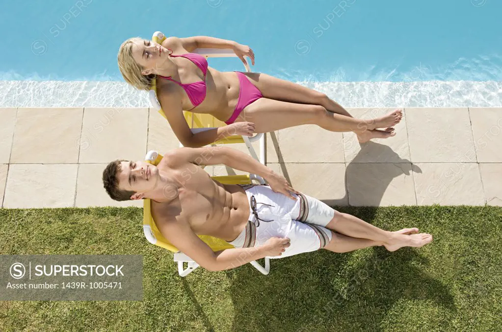 Couple sunbathing by the pool