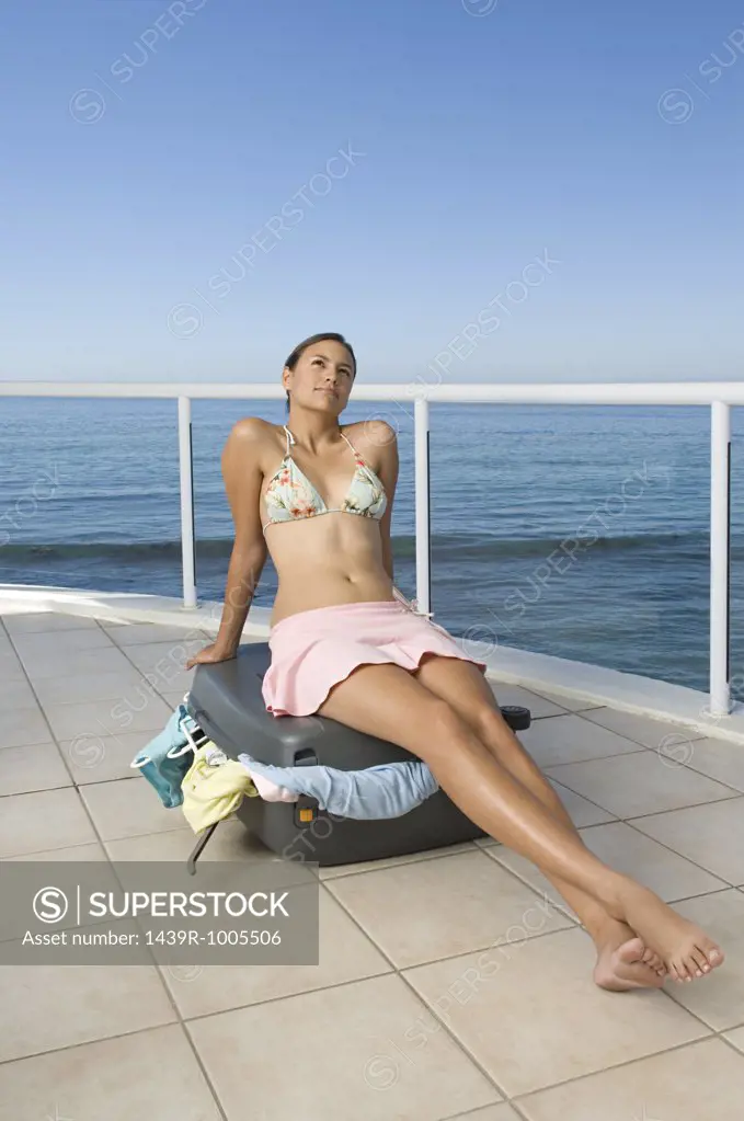 Woman sitting on suitcase