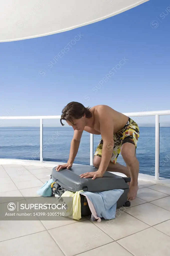 Man trying to close suitcase