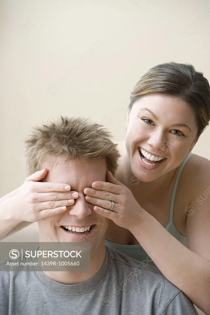 Woman covering husband's eyes