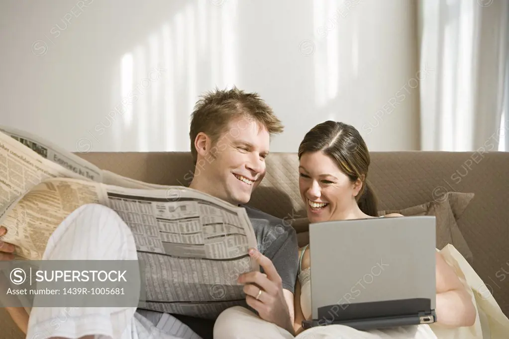 Couple with newspaper and laptop
