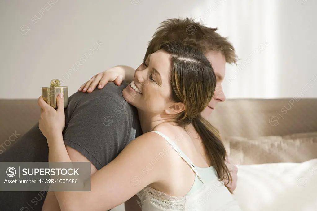 Woman holding gift and hugging husband