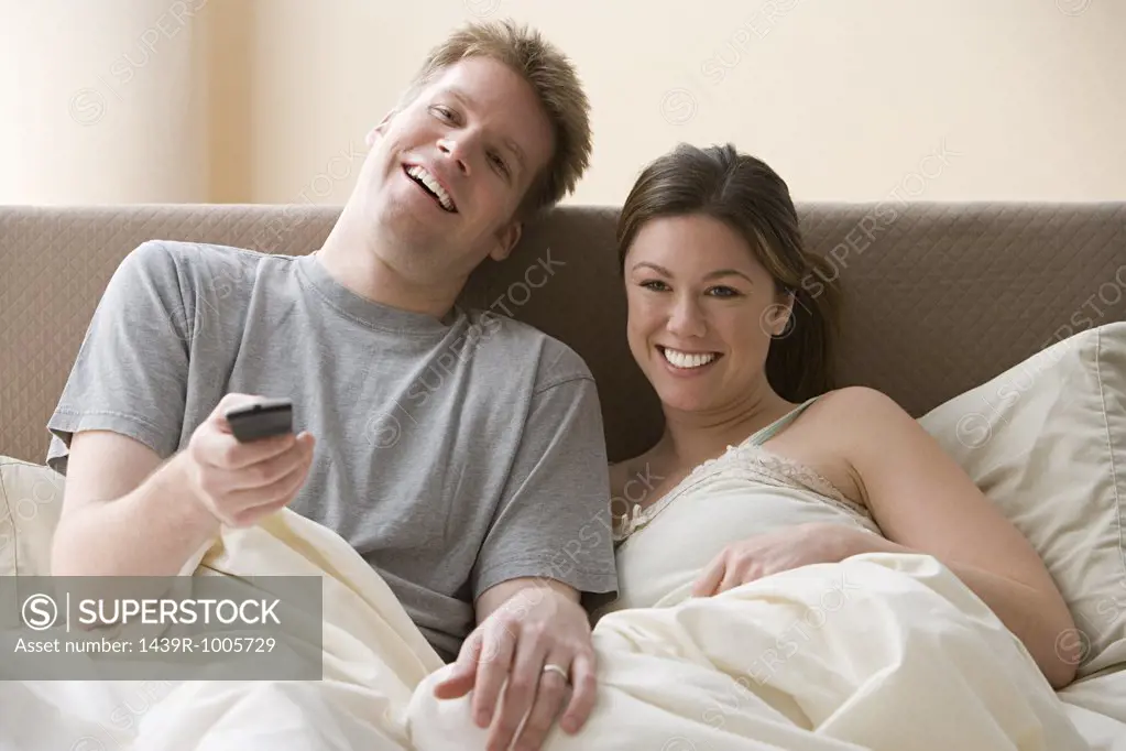 Couple watching television in bed